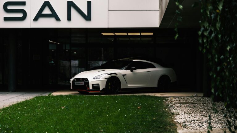 Capture of a white Nissan GT-R NISMO parked at a dealership entrance, showcasing its modern design.