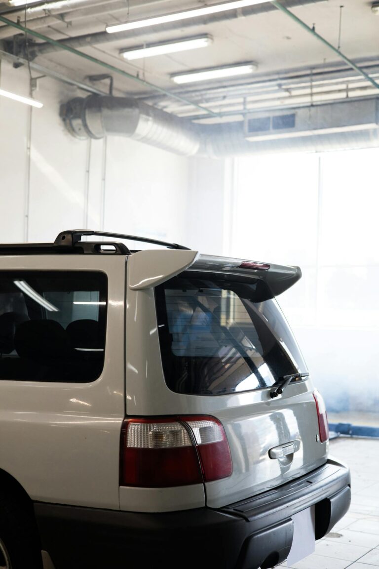 White SUV with tail lights parked inside a sunlit garage, showcasing a vertical perspective.